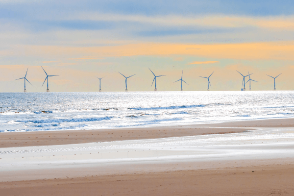 a beach with an offshore windfarm in the distance.